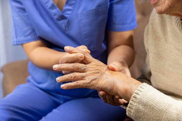 A nurse helping a patient with chronic pain in their hands during winter.