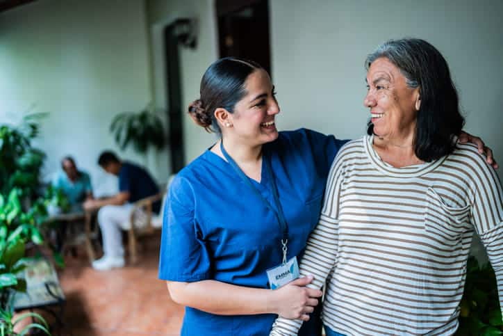 A Nurse Helping An Elderly Woman In A Nursing Home.